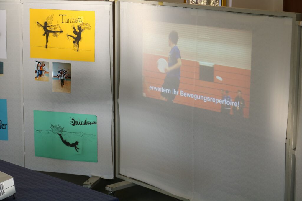 Ein Bildschirm zeigt ein Video eines Sportevents, dahinter sind Informationstafeln.