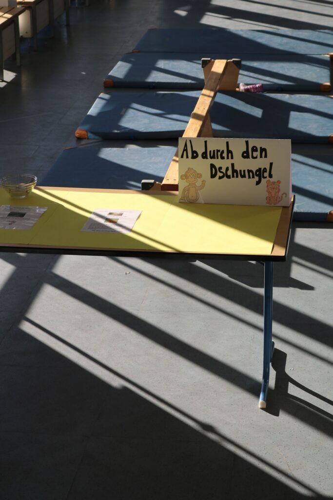 Tisch mit einem Schild "Ab durch den Dschungel" und Materialien in einem hellen Raum.