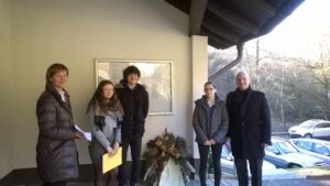 Gruppe von vier Personen steht vor einem Gebäude mit Blumenarrangement.