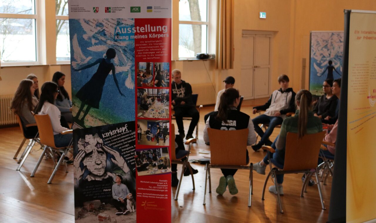 Schüler sitzen in einem Raum und diskutieren um eine Gesprächsrunde.