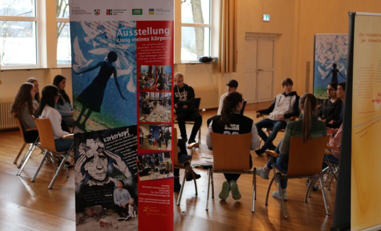Schüler sitzen in einem Raum und diskutieren um eine Gesprächsrunde.