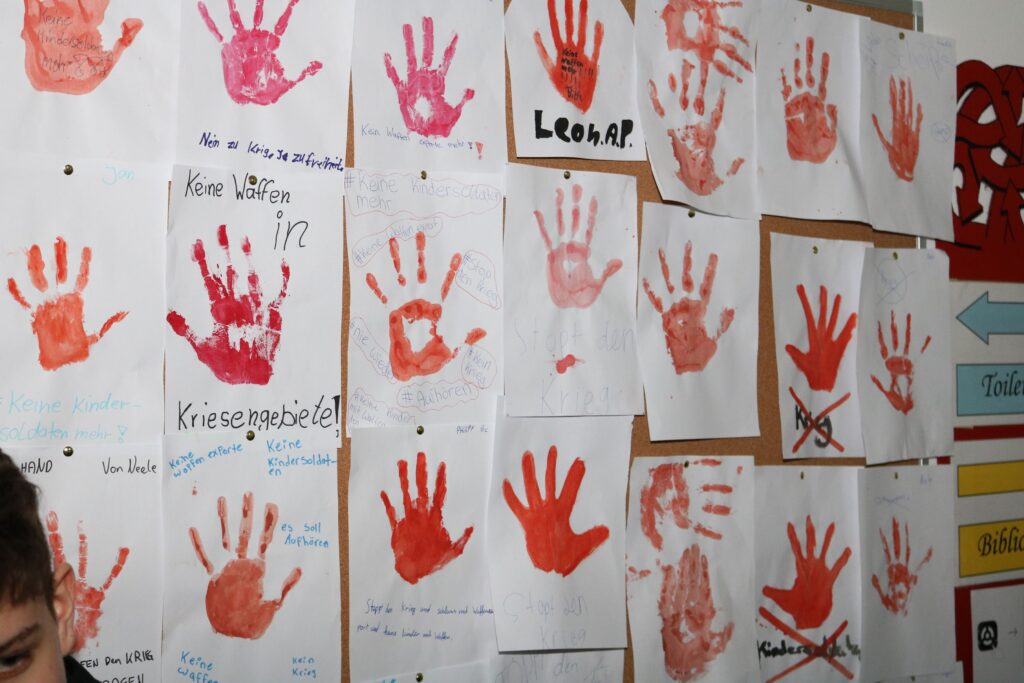 Wand mit bunten Handabdrücken und Kindermalerei.