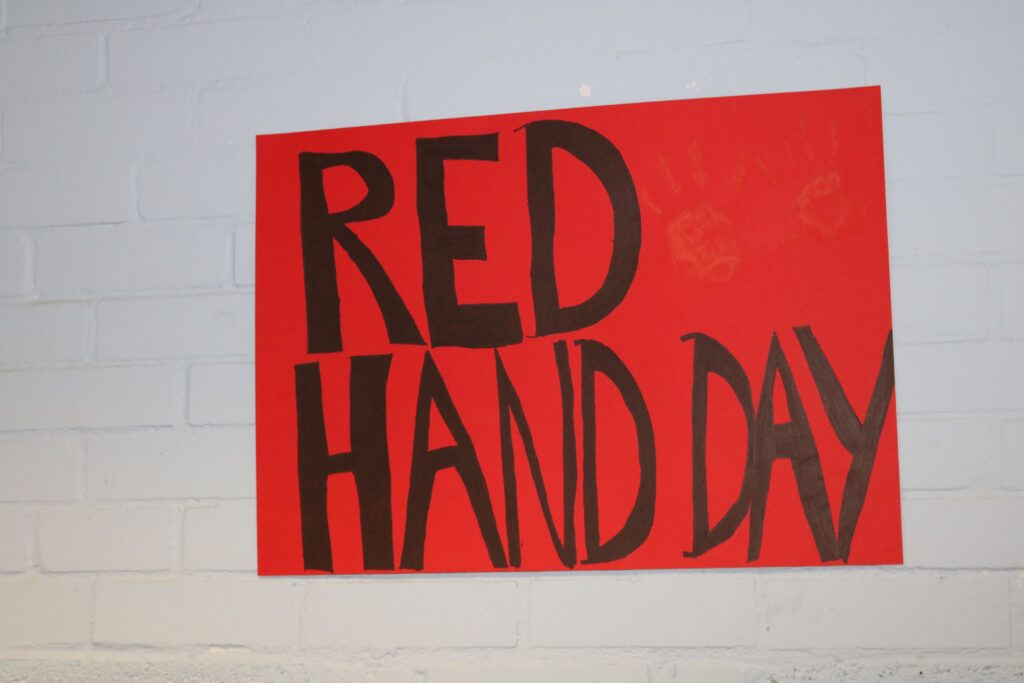 Plakat mit der Aufschrift "RED HAND DAY" in großen schwarzen Buchstaben auf rotem Hintergrund.