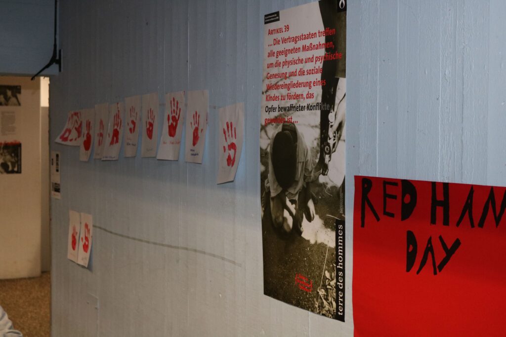Wand mit Handabdrücken und Plakaten in einem Flur.