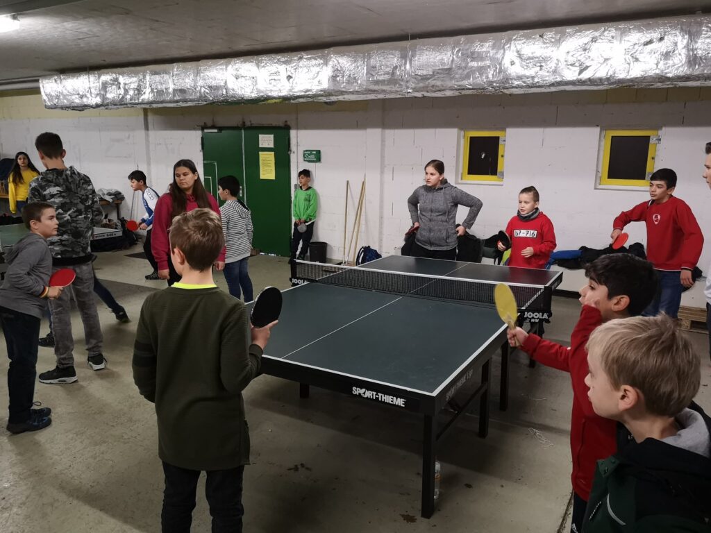Tischtennisspielende Kinder in einem Gruppenraum.