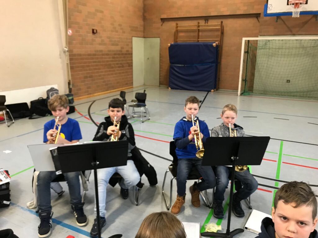 Vier Schüler spielen Trompete in einer Sporthalle.