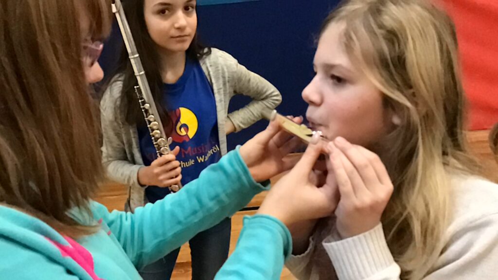Schüler üben gemeinsam das Spielen eines Instruments in der Aula.