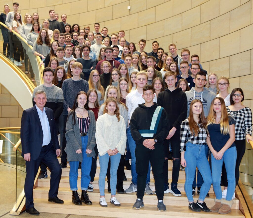 Gruppe von Schülern und Lehrern auf einer Treppe in einem Gebäude.