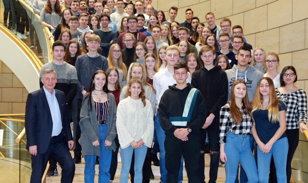 Gruppe von Schülern und Lehrern auf einer Treppe in einem Gebäude.