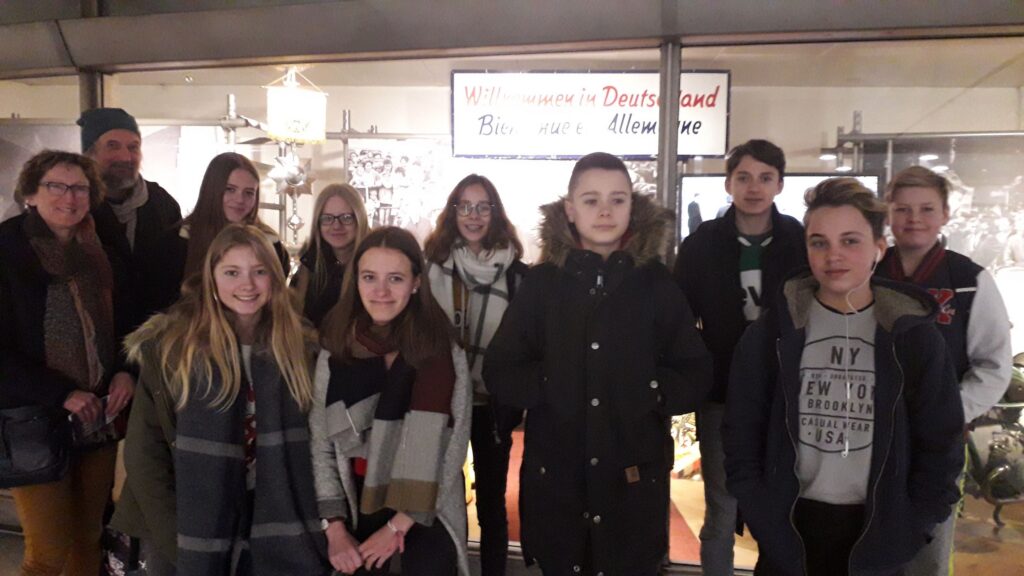 Gruppe von zwölf Personen vor einem Geschäft, lächelnd und zusammengestellt.