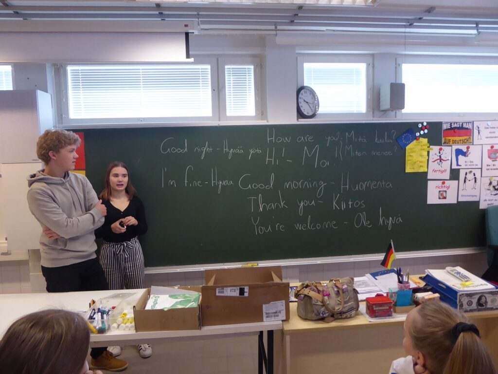 Schüler präsentieren an der Tafel, Deutsch und Englisch stehen geschrieben.