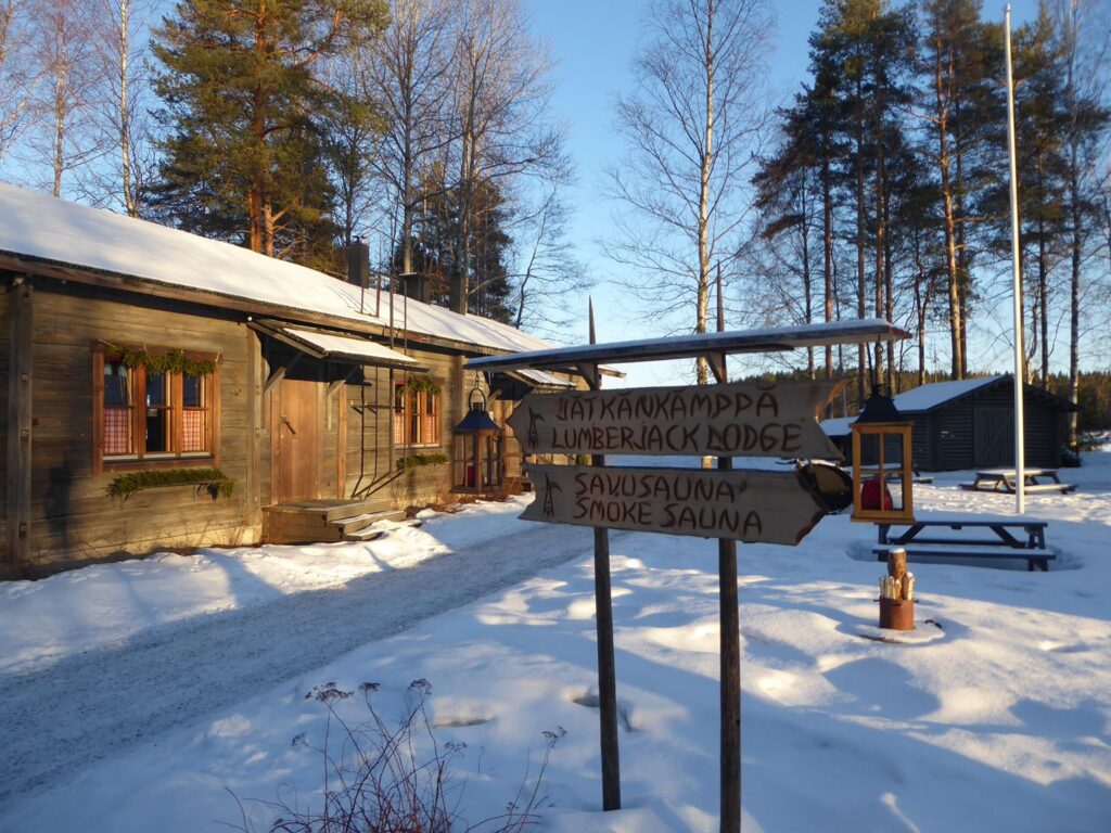Ein Holzgebäude mit Wegweisern in einer verschneiten Landschaft.