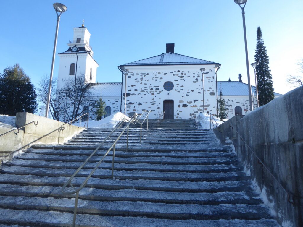 Das Bild zeigt eine Kirche im Schnee mit steilen Treppen.