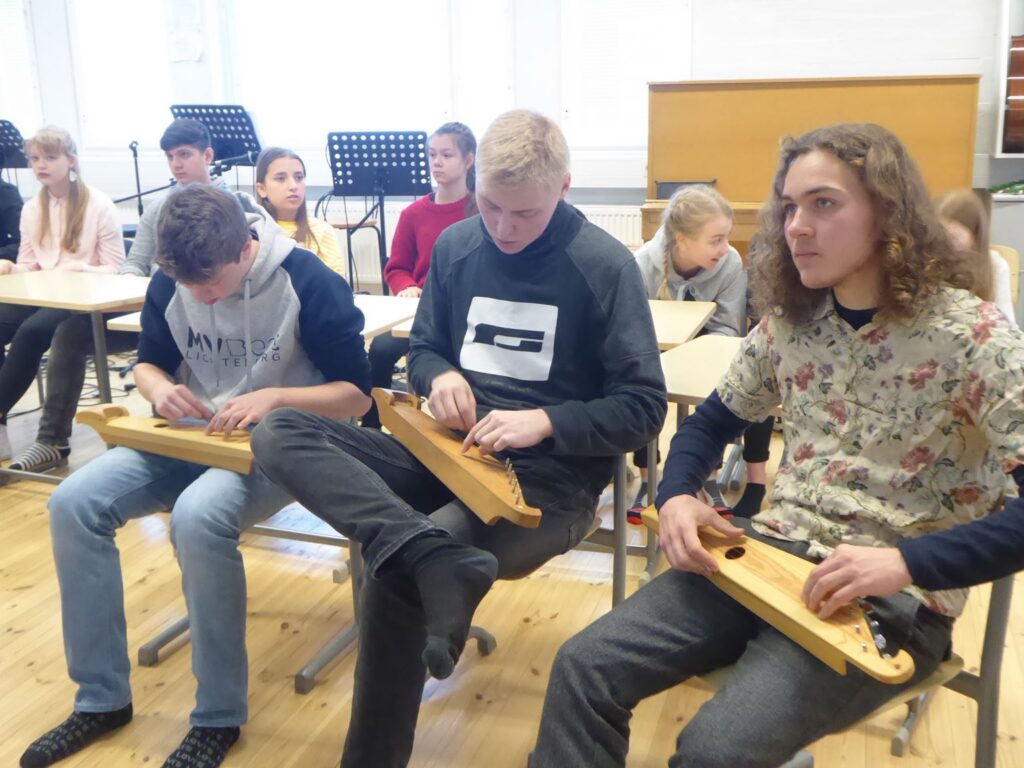 Schüler sitzen im Klassenzimmer und spielen Musikinstrumente.