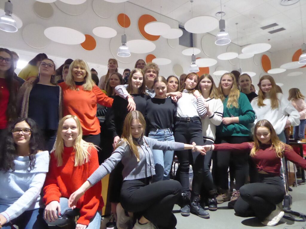 Gruppenfoto von Schülerinnen in einem hellen Raum mit runden Deckenleuchten.