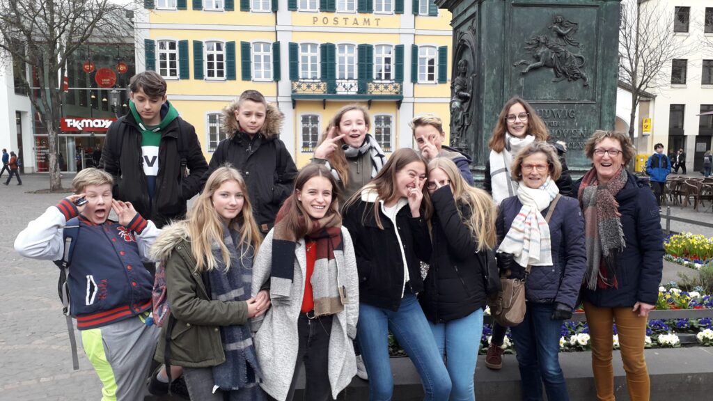 Gruppe von Jugendlichen und Erwachsenen posiert fröhlich an einem Platz.