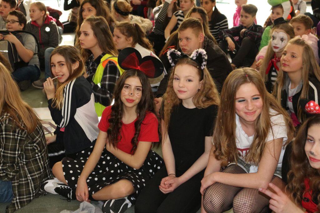 Schülerinnen und Schüler sitzen zusammen in einer Gruppe, lächeln und schauen aufmerksam.