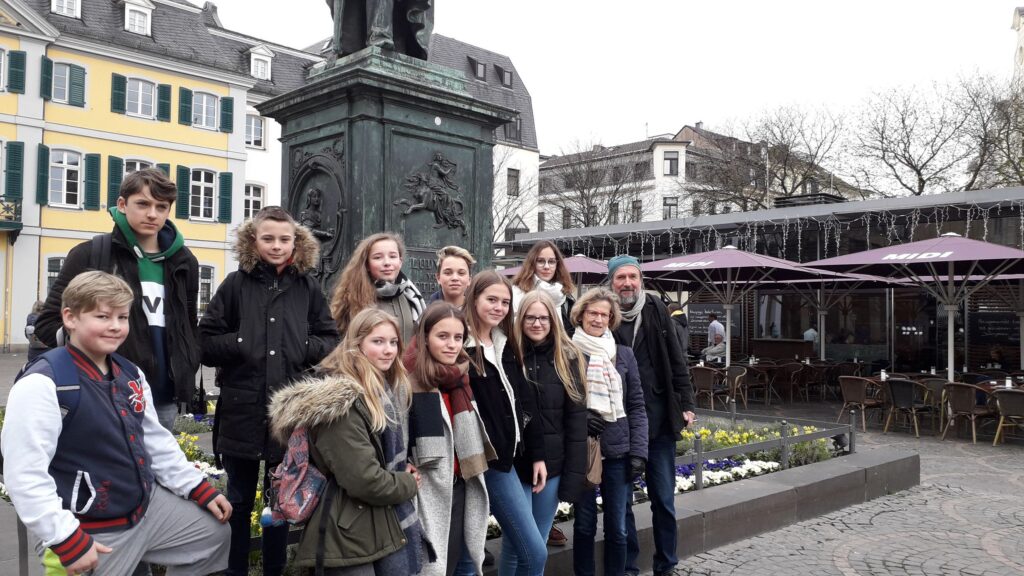 Gruppe von Jugendlichen vor einem Denkmal auf einem Platz.