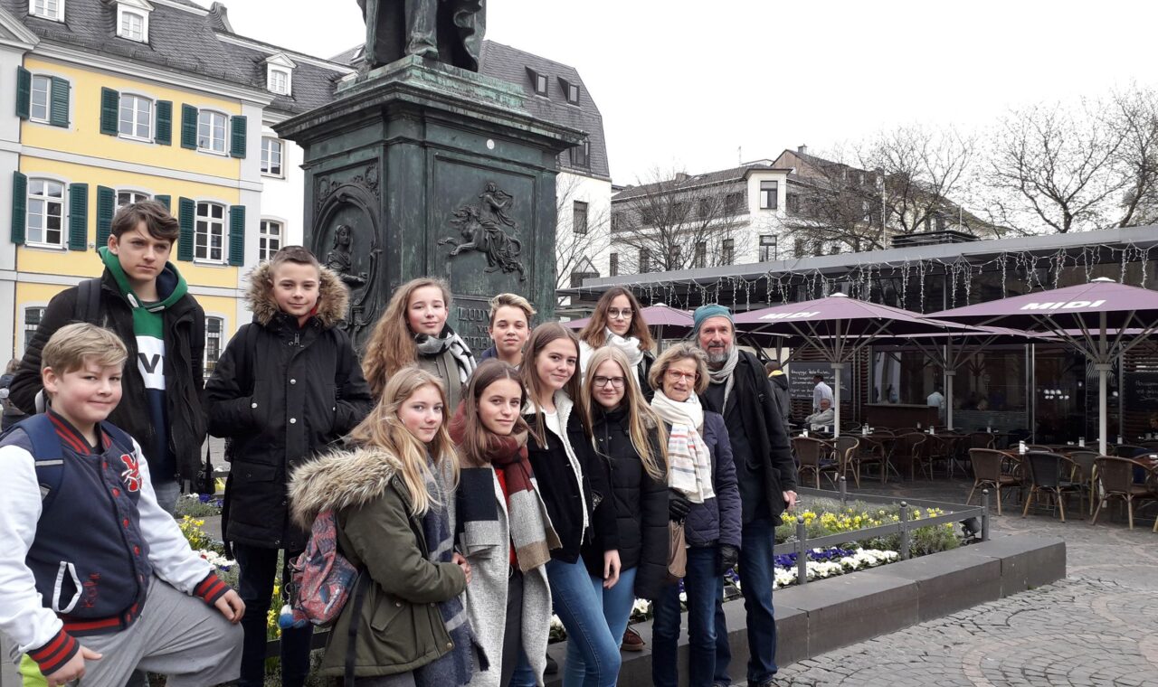 Gruppe von Jugendlichen vor einem Denkmal auf einem Platz.