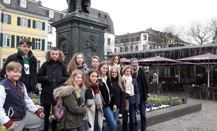 Gruppe von Jugendlichen vor einem Denkmal auf einem Platz.