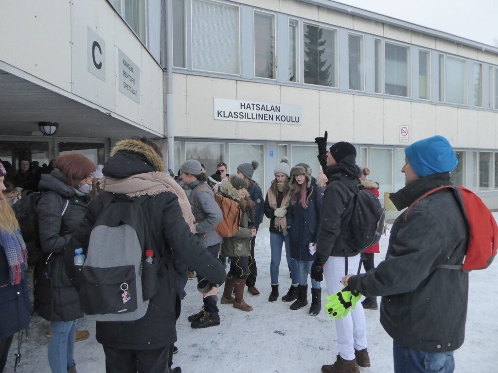 Schülerinnen und Schüler stehen vor einem Schulgebäude im Schnee.