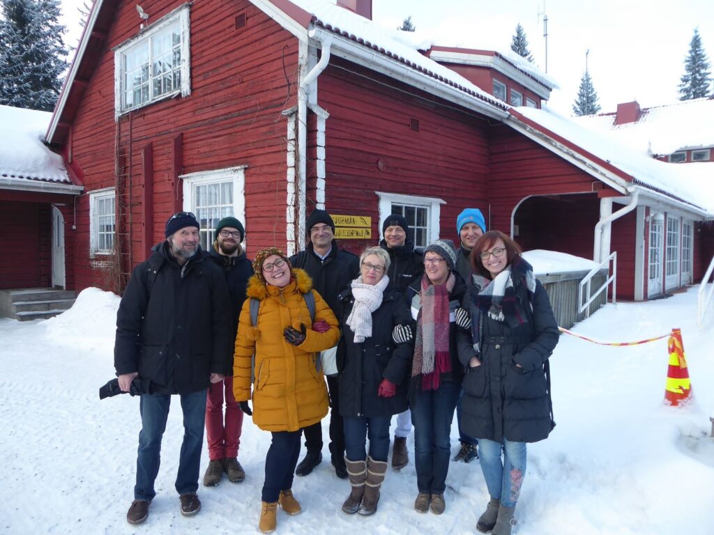 Gruppe von Personen vor einem roten Gebäude im Schnee.