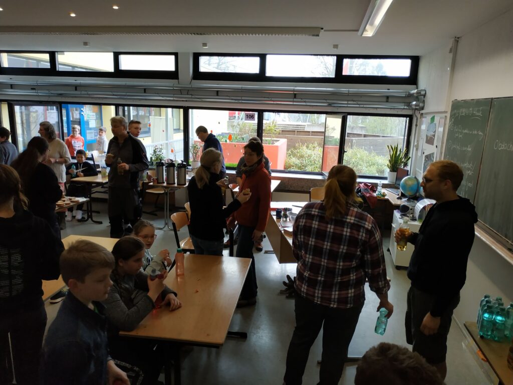Aktivitäten in einem Klassenraum mit mehreren Personen und Tischen.