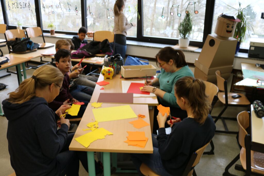 Schüler arbeiten an Bastelprojekten an einem Tisch im Klassenraum.