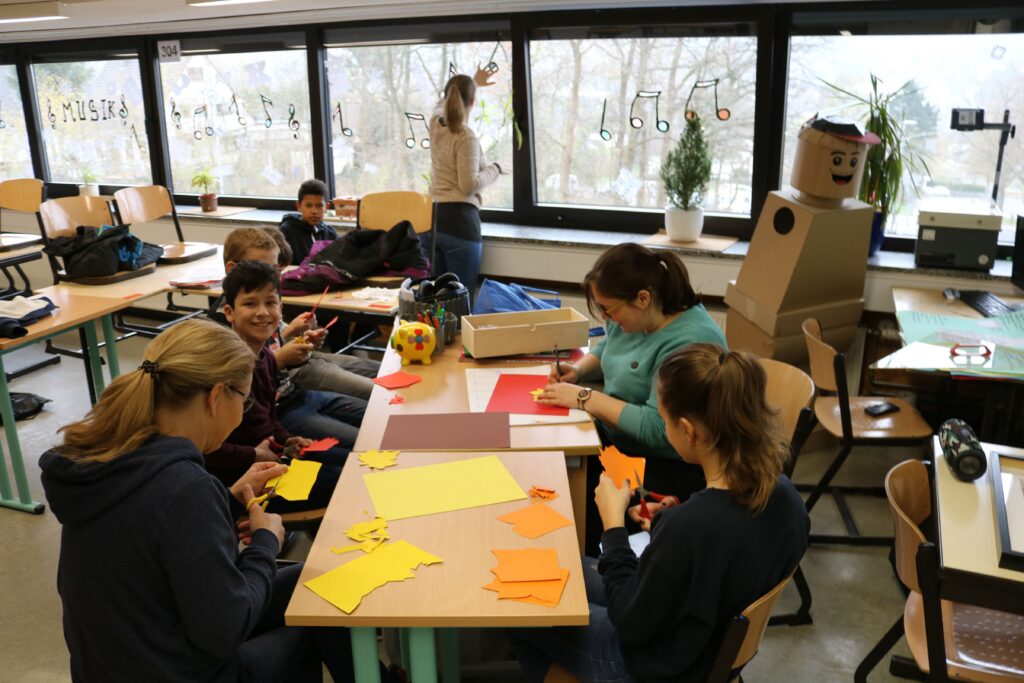Schüler arbeiten an Bastelprojekten an einem Tisch im Klassenraum.