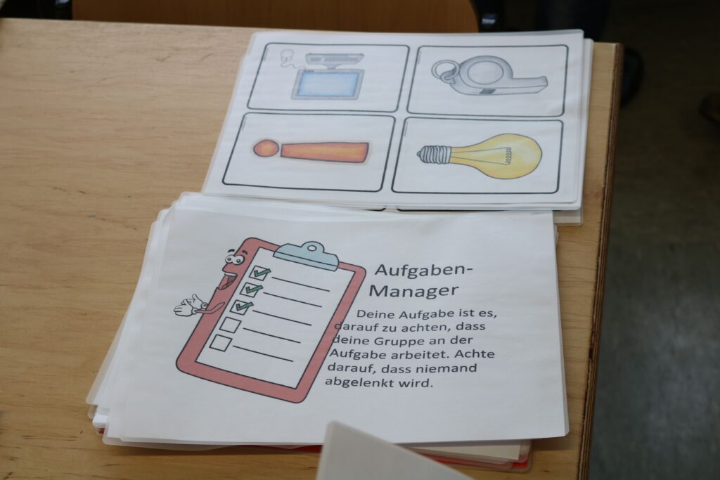 Auf einem Tisch liegen Arbeitsblätter mit Aufgaben und Illustrationen.