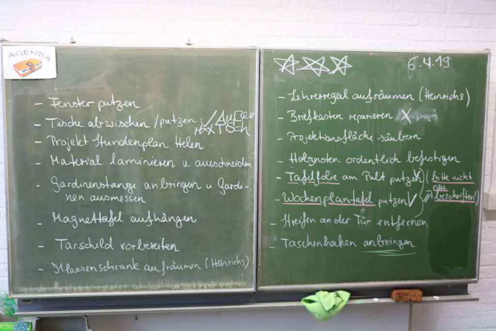 Zwei grüne Tafeln mit handschriftlichen Notizen und Aufgaben.