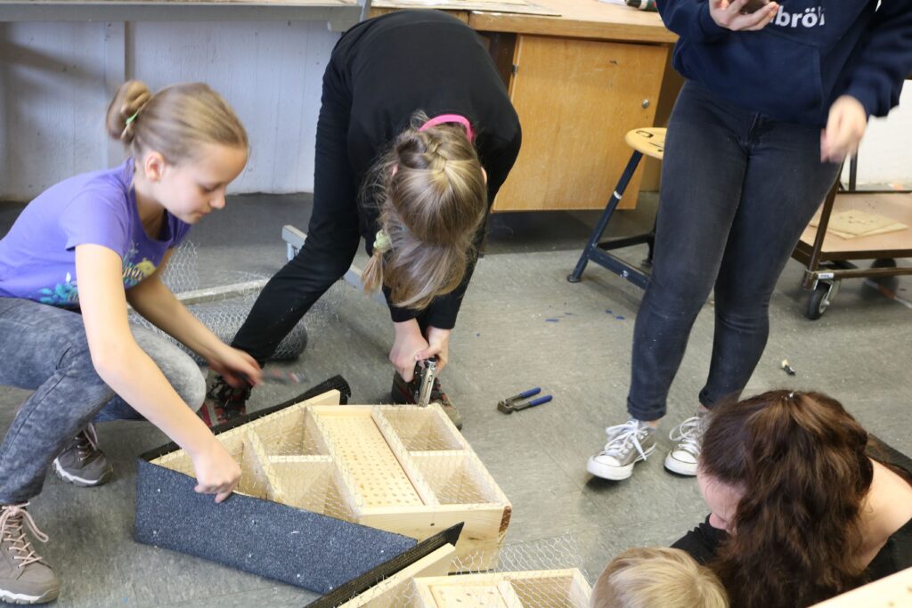 Schülerinnen arbeiten gemeinsam an einem Holzprojekt in der Werkstatt.