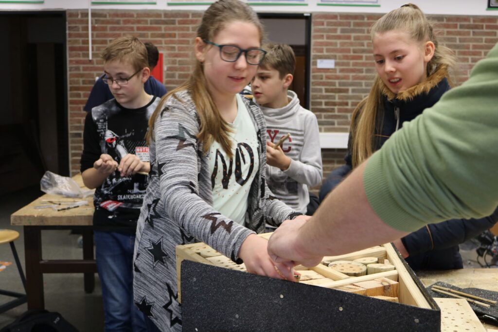 Schüler arbeiten an einem Projekt mit Holzmaterialien in einem Klassenraum.