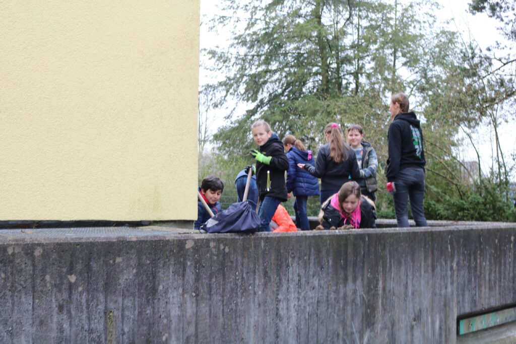 Gruppe von Kindern spielt an einer Mauer neben einem gelben Gebäude.