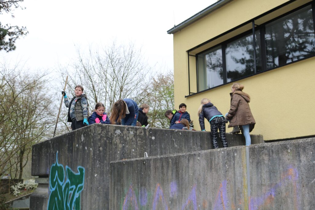 Kinder spielen und klettern auf einer Mauer neben einem Gebäude.