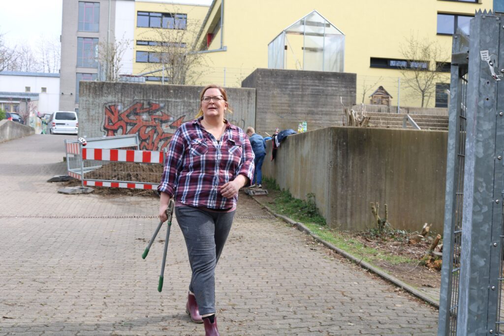 Frau mit Wanderstock läuft auf einem Platz zwischen Gebäuden.