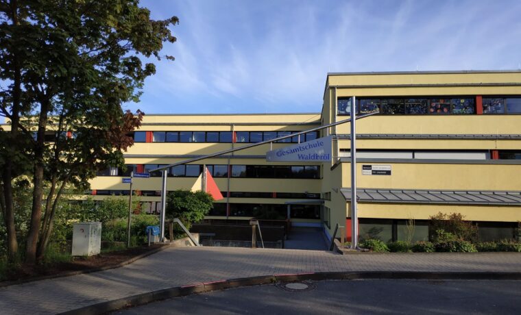 Schulgebäude mit einem großen Eingangsbereich und bunten Fenstern.