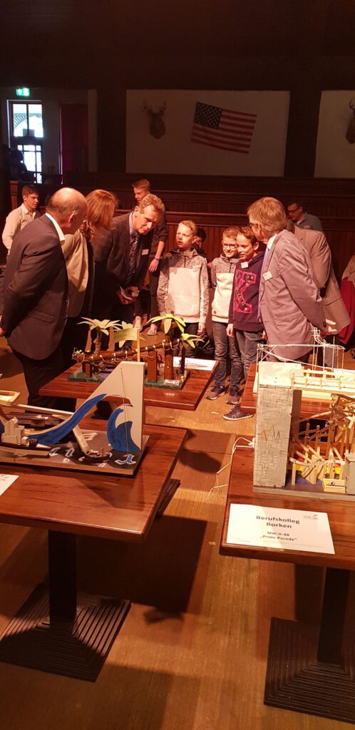 Schüler präsentieren ihre Projekte in einem Saal mit Zuschauern.