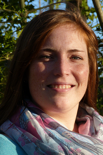 Portrait einer lächelnden Frau mit braunen Haaren und buntem Schal.