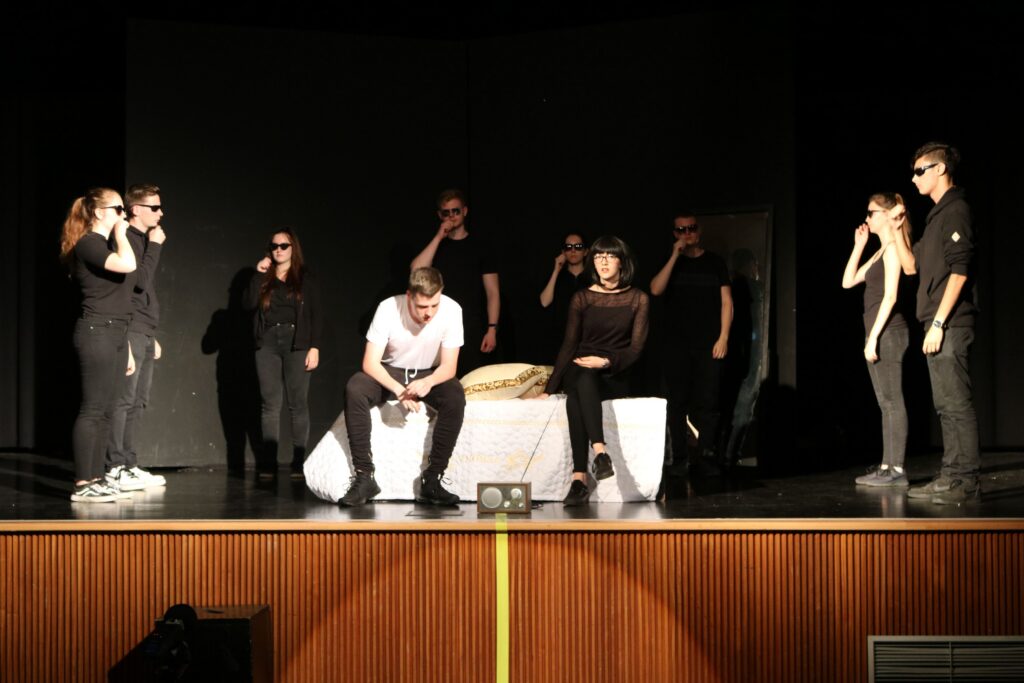 Theateraufführung mit darstellenden Schülern auf einer Bühne.