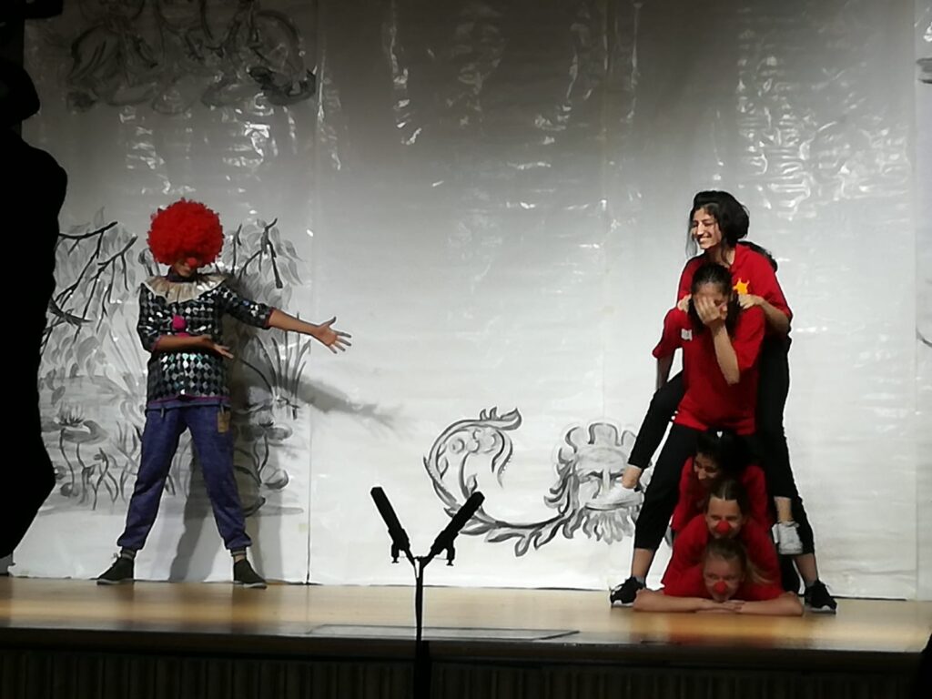 Kinder führen eine Theateraufführung auf der Bühne auf.