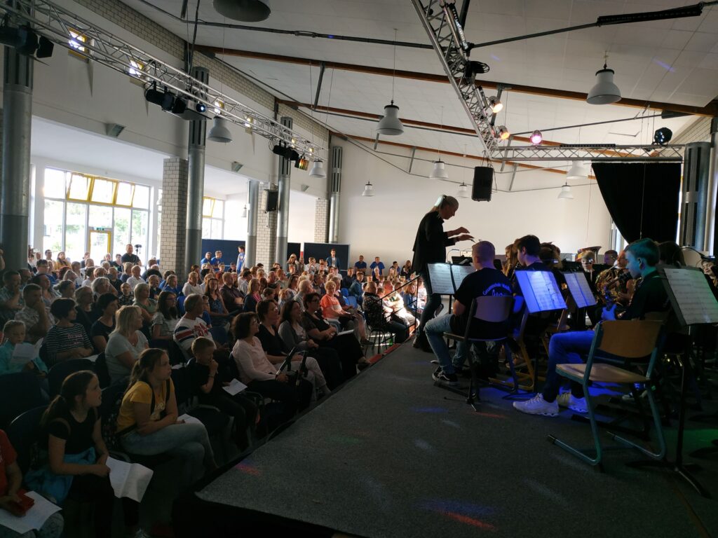 Konzert mit vielen Zuschauern in einem großen Saal. Musiker auf der Bühne.