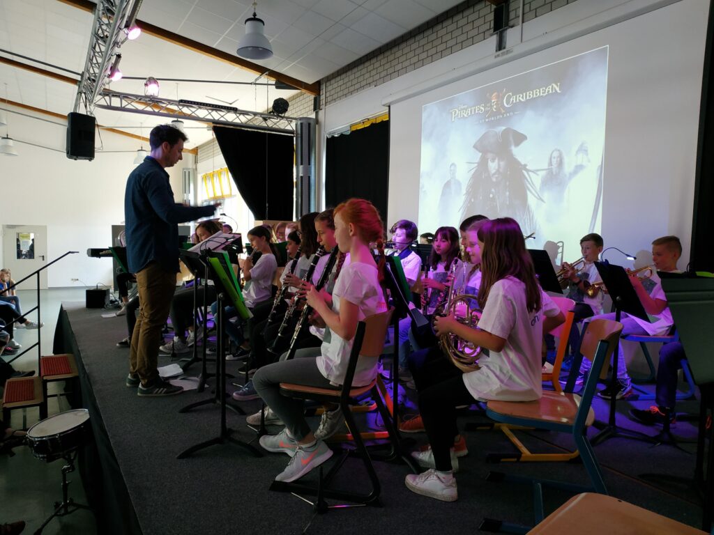 Schülerinnen und Schüler spielen in einem Ensemble auf der Bühne.