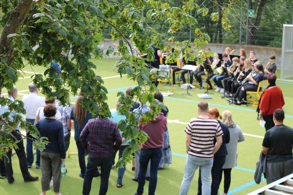 Menschen beobachten eine Veranstaltung im Freien auf einem Sportplatz.