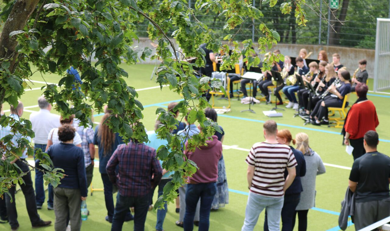 Menschen beobachten eine Veranstaltung im Freien auf einem Sportplatz.