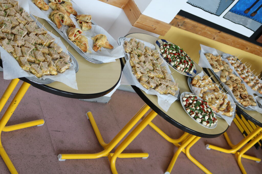 Platten mit verschiedenen Fingerfood-Snacks auf Tischen in einem Raum.