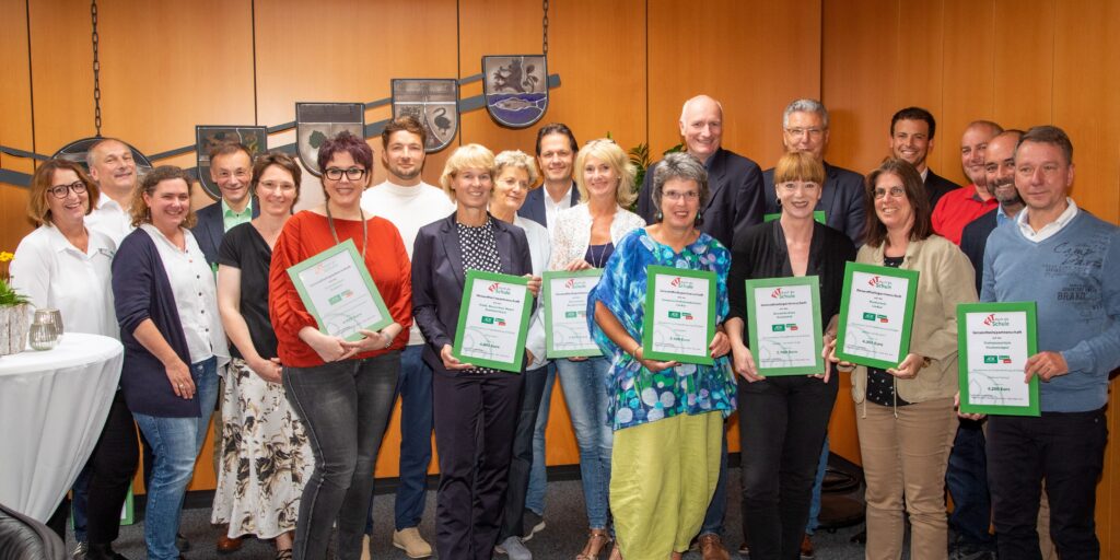 Gruppenfoto von Personen mit Urkunden in einem Raum.