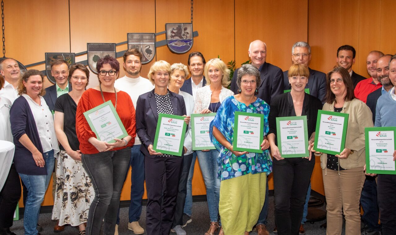 Gruppenfoto von Personen mit Urkunden in einem Raum.