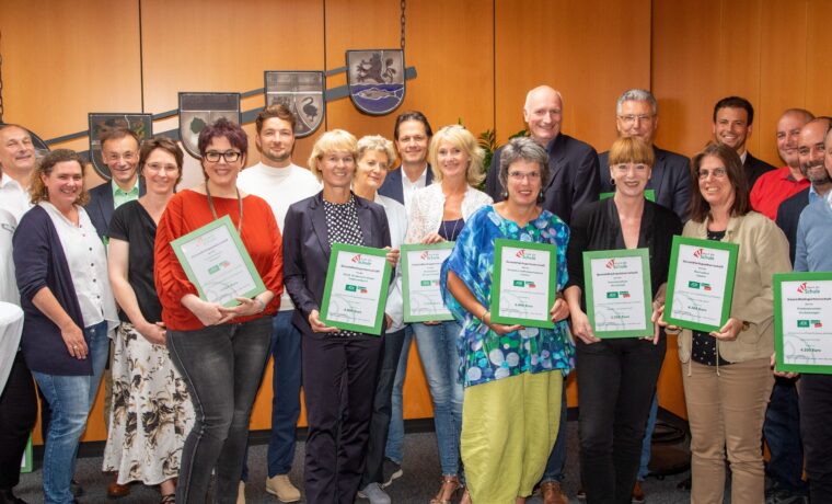 Gruppenfoto von Personen mit Urkunden in einem Raum.