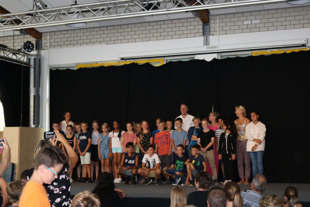 Gruppe von Schülern und Lehrern auf der Bühne bei einer Veranstaltung.